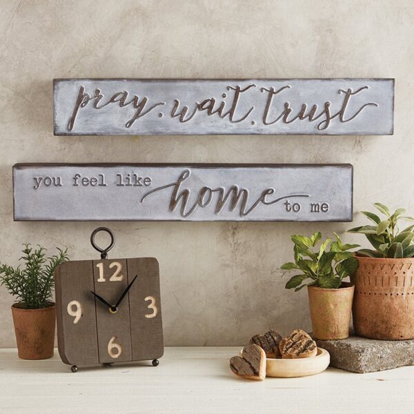 A clock and two signs on top of a table.