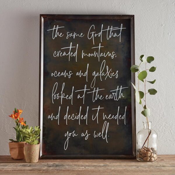 A framed sign with the words " the same god that created mountains, oceans and galaxies.