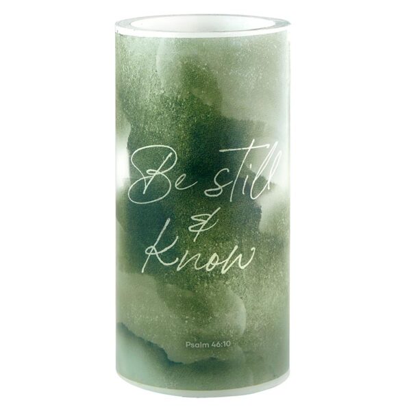 A candle that has the words be still and know written on it.