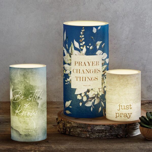 Three candles on a table with the words " prayer changes things ".