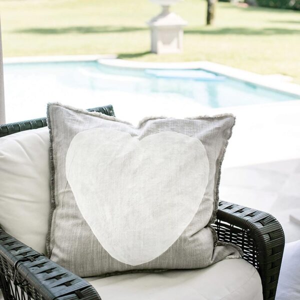 A white chair with a heart pillow on it