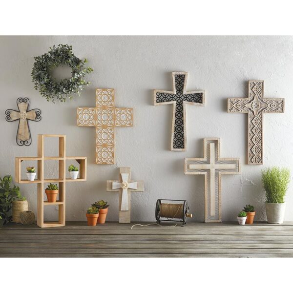 A group of crosses on display in front of a wall.