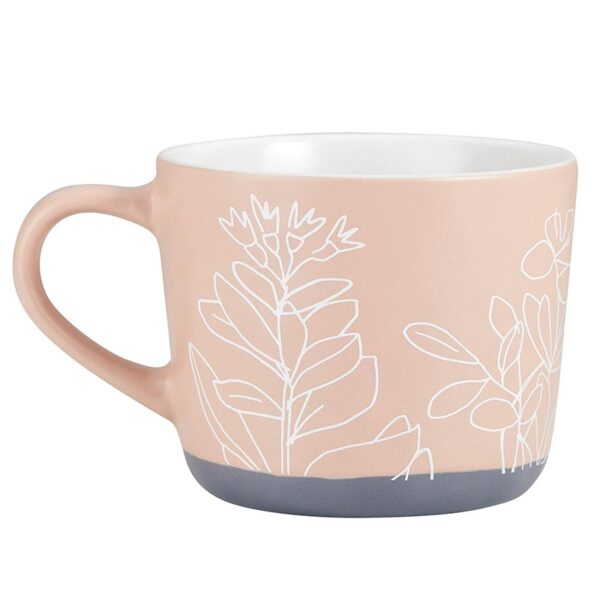 A pink mug with white plants on it.