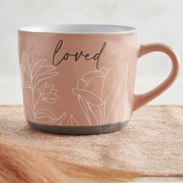 A pink coffee mug with the word " loved " written on it.