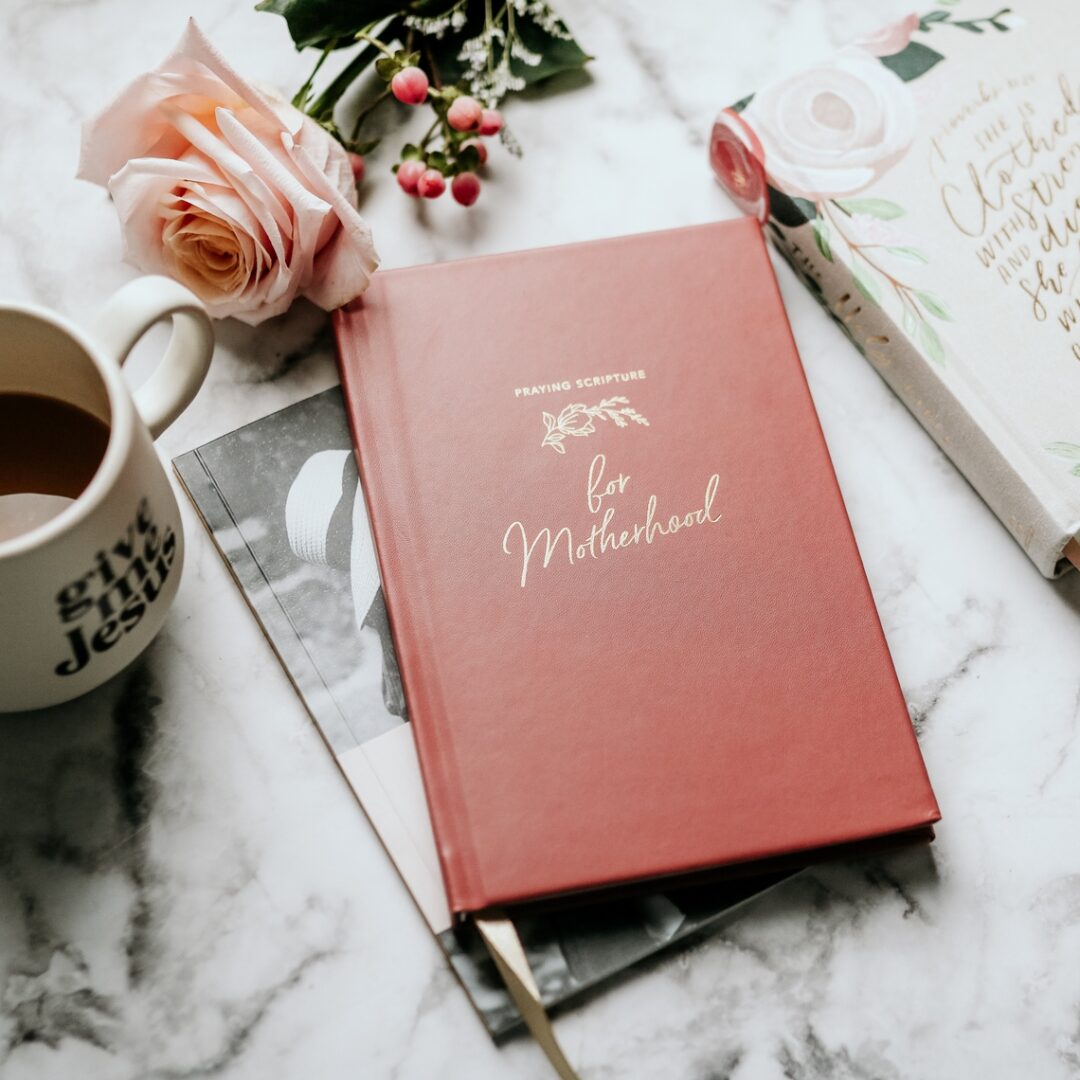 A red book sitting on top of a table next to a cup.