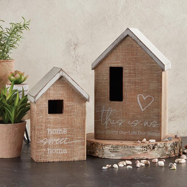 Two wooden houses with a white board on the side of them.