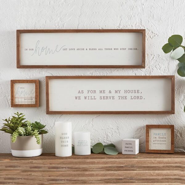 A wooden table topped with potted plants and framed pictures.