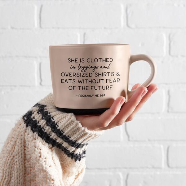 A person holding a coffee mug with the words " she is clothes in progress ".